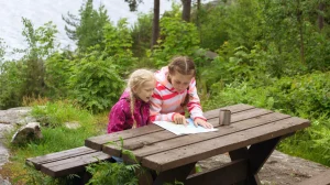 Barn som ser på kart, på en rastebenk